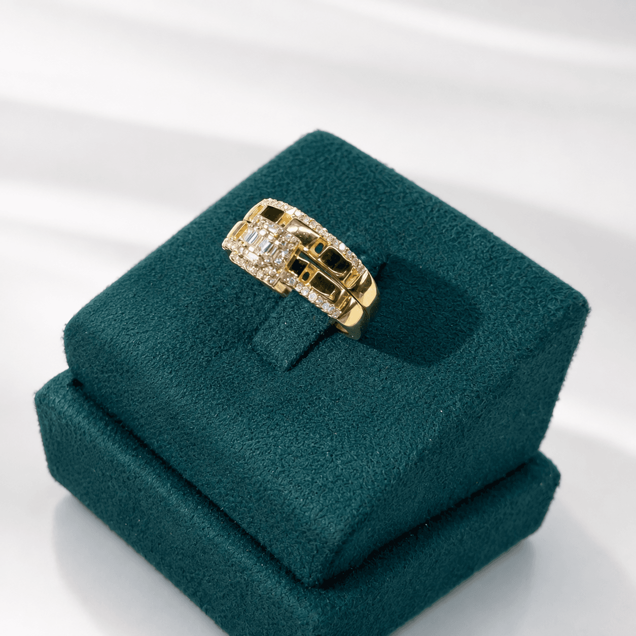 Gold ring with a diamond cluster centerpiece on a dark green velvet display stand.