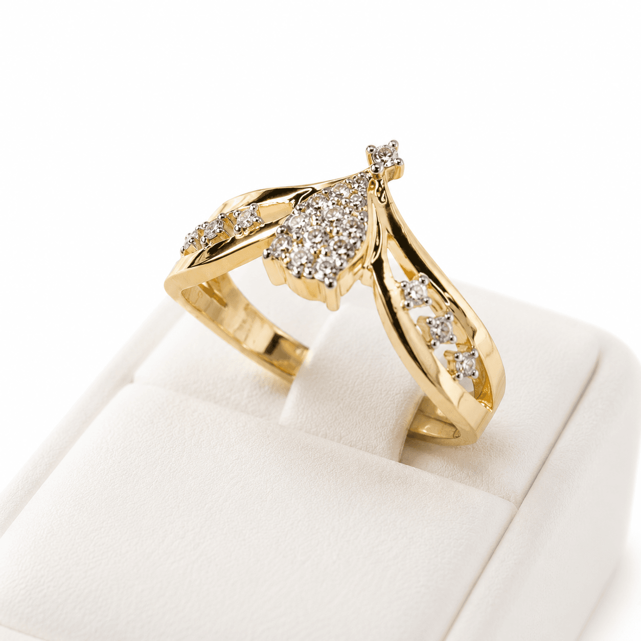 Gold ring with a teardrop diamond cluster and diamond-set band on a white jewelry box.